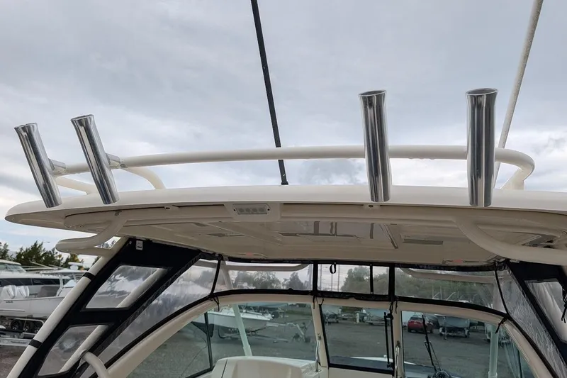 Slide: The Image of 2011 Pursuit DC 265 Dual Console boat with rod holders and canopy under cloudy sky. - 27