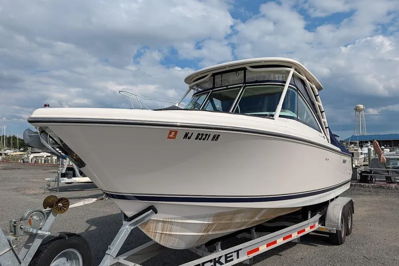 Slide: The Image of 2011 Pursuit DC 265 Dual Console boat on trailer, parked outdoors under cloudy sky. - 3