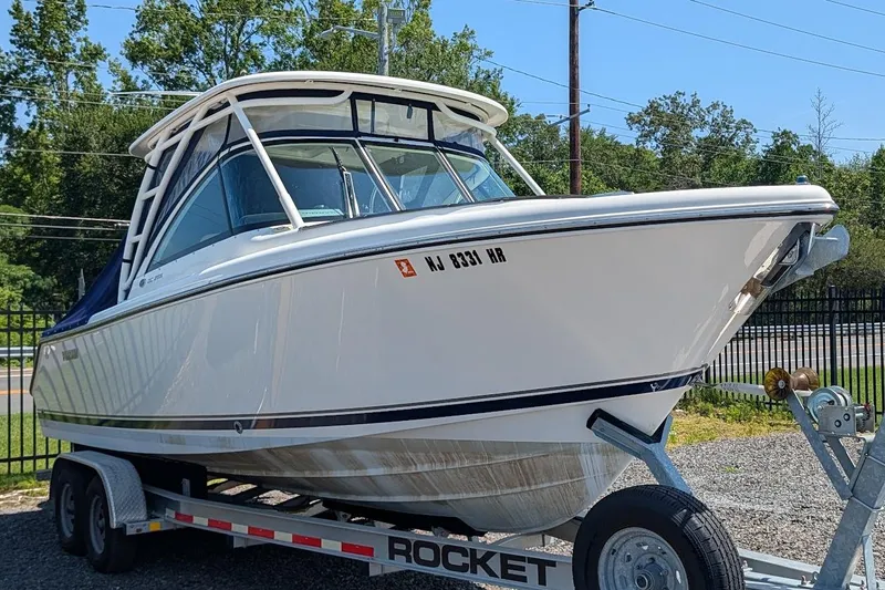 The Image of 2011 Pursuit DC 265 Dual Console boat on trailer, parked outdoors. - 0