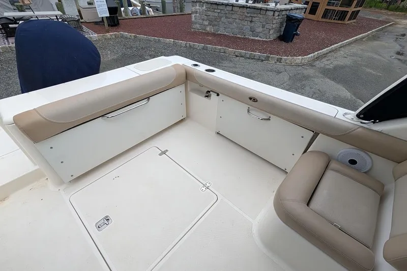 Slide: The Image of 2011 Pursuit DC 265 Dual Console boat interior with beige seating and storage compartments. - 8