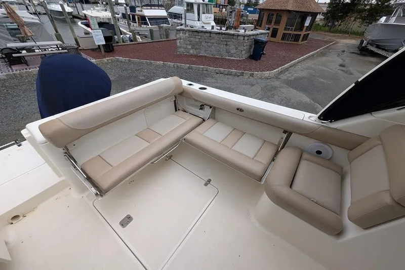 Slide: The Image of 2011 Pursuit DC 265 Dual Console boat interior with beige seating, docked at marina. - 9