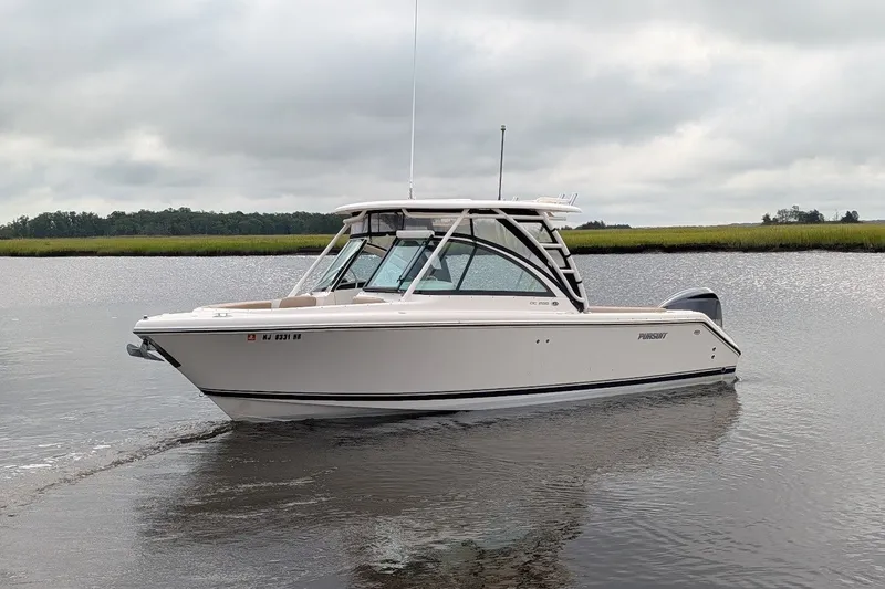 Slide: The Image of 2011 Pursuit DC 265 Dual Console boat on calm water under cloudy skies. - 2