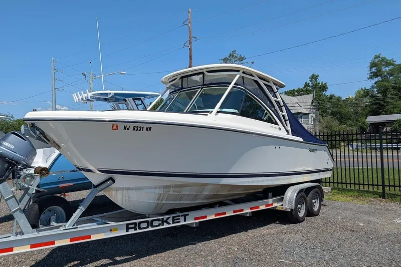 Slide: The Image of 2011 Pursuit DC 265 Dual Console boat on trailer, parked outdoors. - 1