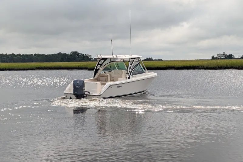 Slide: The Image of 2011 Pursuit DC 265 Dual Console boat cruising on a calm river under cloudy skies. - 4