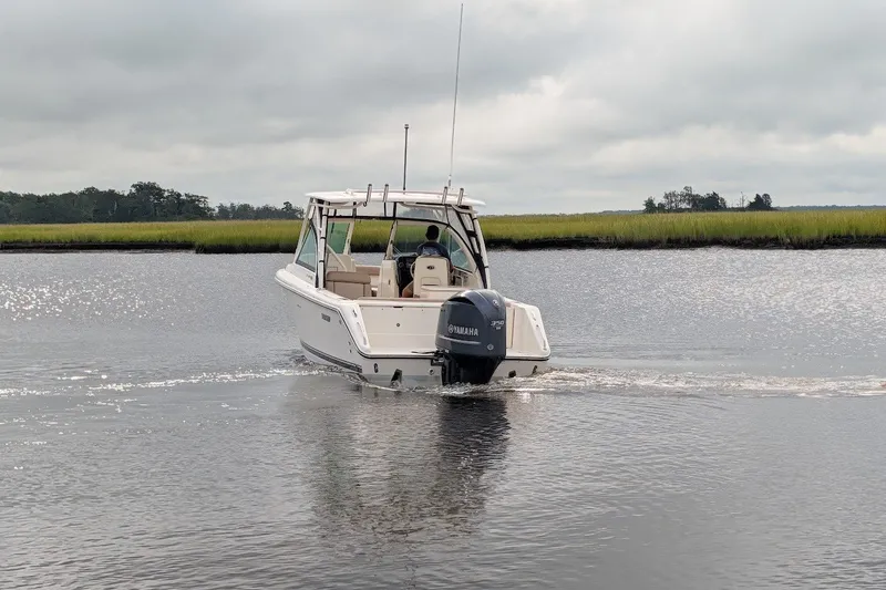 Slide: The Image of 2011 Pursuit DC 265 Dual Console boat cruising on a calm river under cloudy skies. - 3