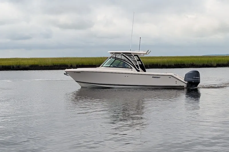 Slide: The Image of 2011 Pursuit DC 265 Dual Console boat cruising on calm water under cloudy skies. - 5