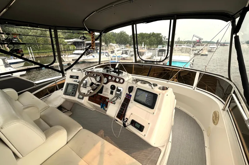 Slide: The Image of Interior view of 2000 Silverton 422 Motor Yacht helm with marina background. - 21