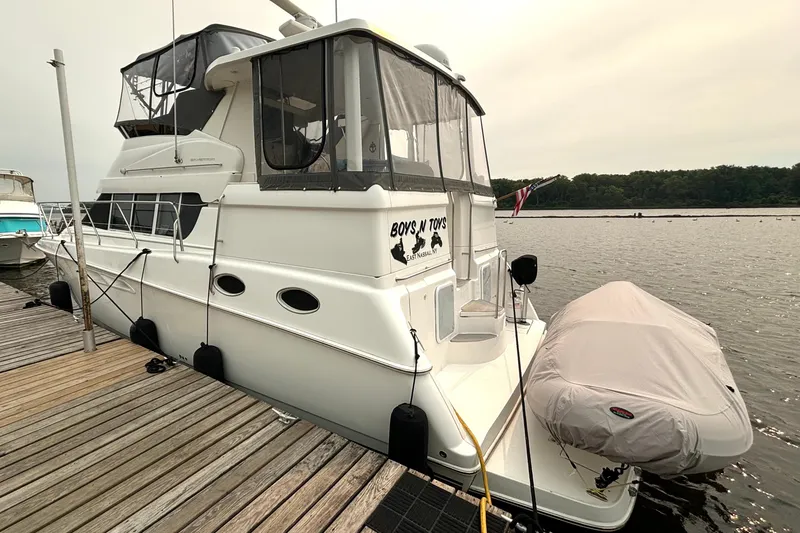 Slide: The Image of 2000 Silverton 422 Motor Yacht docked with covered dinghy, side view. - 4