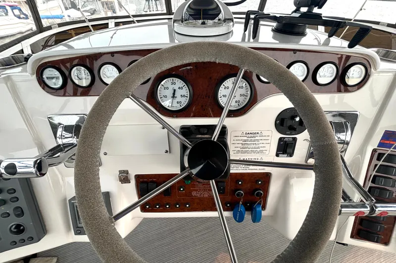 Slide: The Image of Steering wheel and dashboard of a 2000 Silverton 422 Motor Yacht, featuring gauges and controls. - 25