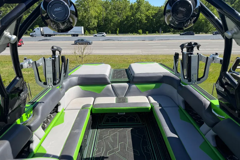 Slide: The Image of 2022 Moomba Makai boat interior with green and gray seating, speakers, and wakeboard racks. - 13