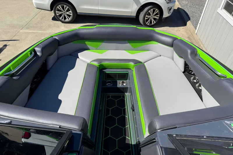 Slide: The Image of 2022 Moomba Makai boat interior with gray and green seating, parked beside a white car. - 2