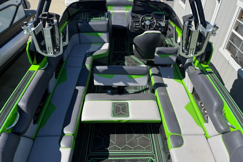 Slide: The Image of 2022 Moomba Makai boat interior with green and gray seating, advanced dashboard, and wakeboard racks. - 20