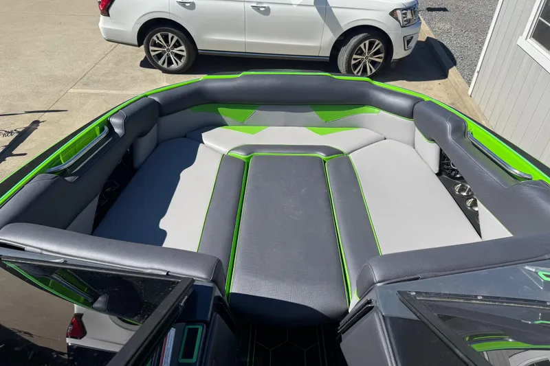 Slide: The Image of 2022 Moomba Makai boat interior with gray and green seating, parked beside a white vehicle. - 3