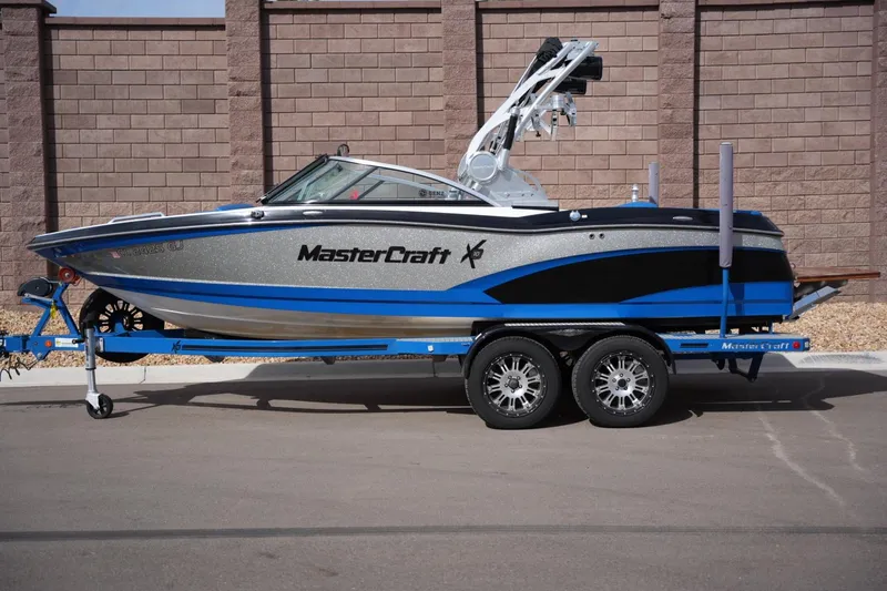The Image of 2016 MasterCraft X10 boat on trailer, parked outdoors, showcasing sleek design and vibrant colors. - 1