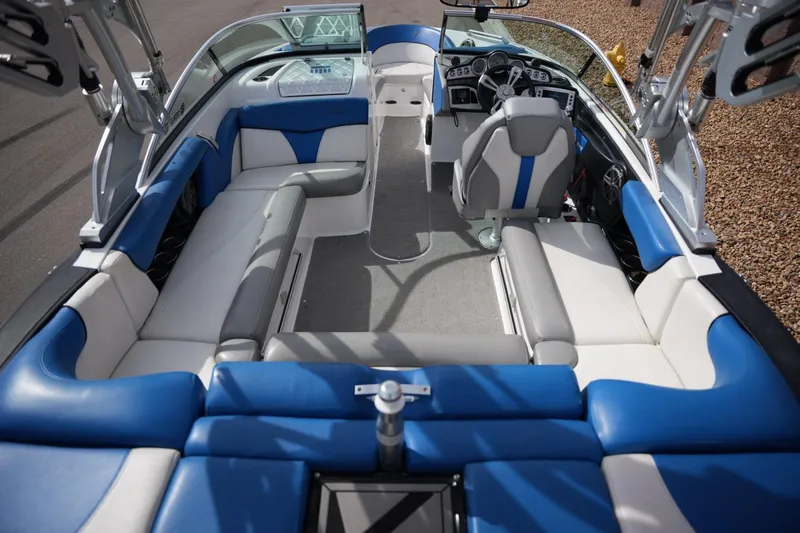 Slide: The Image of 2016 MasterCraft X10 boat interior with blue and white seating, steering console, and spacious layout. - 18