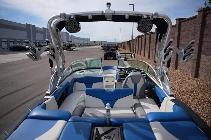 Slide: The Image of 2016 MasterCraft X10 boat interior with blue and white seating, parked near industrial buildings. - 19