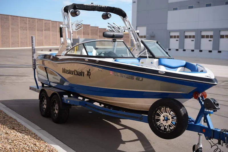 Slide: The Image of 2016 MasterCraft X10 boat on trailer, blue and white design, parked outdoors. - 6