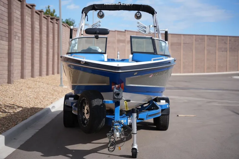 Slide: The Image of 2016 MasterCraft X10 boat on trailer, parked on paved road near brick wall. - 7