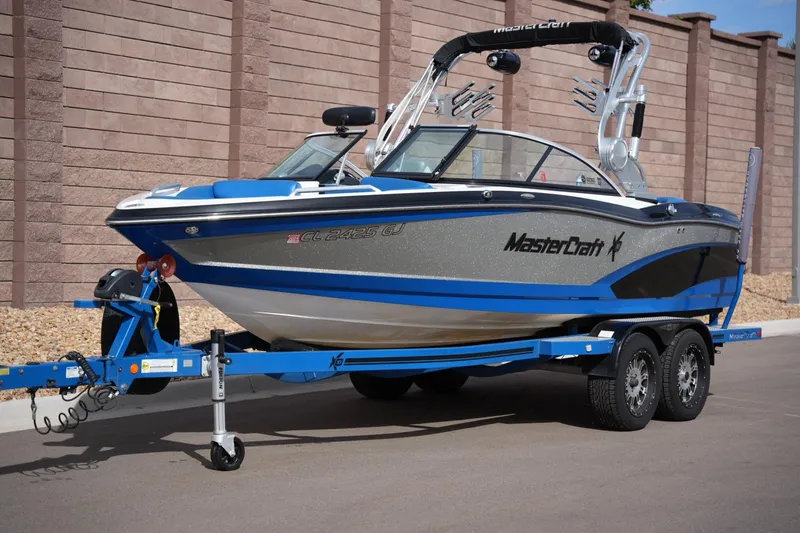 Slide: The Image of 2016 MasterCraft X10 boat on trailer, blue and silver design, parked outdoors. - 8