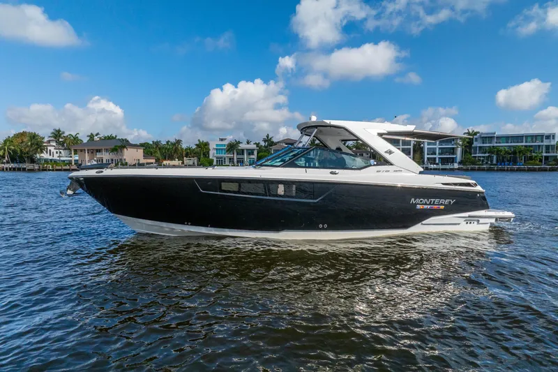 Slide: The Image of 2022 Monterey 378SS Super Sport boat on a sunny day, cruising near waterfront homes. - 5