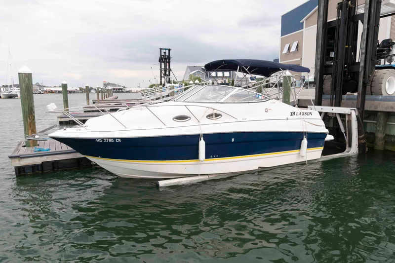 The Image of 2006 Larson Cabrio 240 boat docked at marina, featuring sleek design and blue accents. - 0
