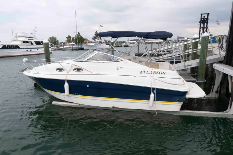 Slide: The Image of 2006 Larson Cabrio 240 boat docked at marina with canopy and sleek design. - 1