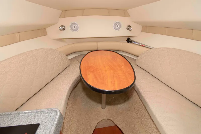 Slide: The Image of 2006 Larson Cabrio 240 cabin interior with beige seating and wooden table. - 10
