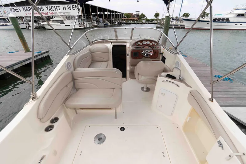 Slide: The Image of 2006 Larson Cabrio 240 boat interior with seating and steering wheel at marina. - 2