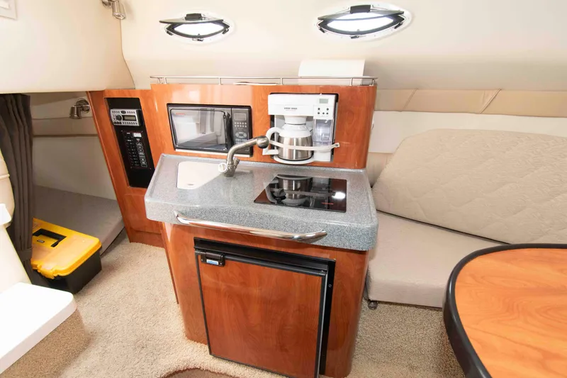 Slide: The Image of 2006 Larson Cabrio 240 interior with kitchenette, featuring sink, microwave, and compact fridge. - 9