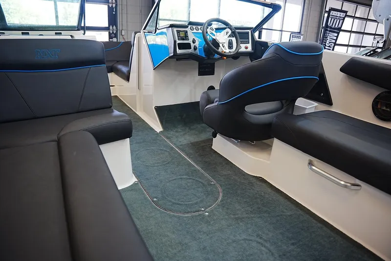 Slide: The Image of 2019 MasterCraft NXT22 boat interior with black seating and blue accents. - 13
