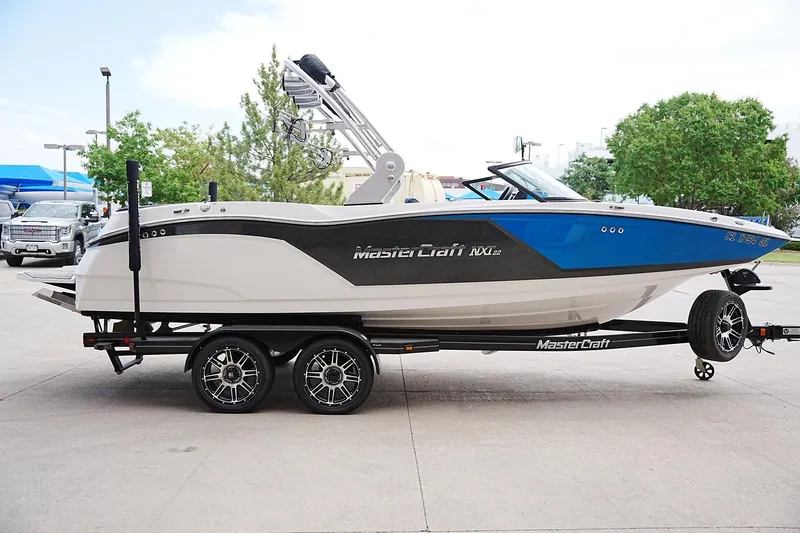 Slide: The Image of 2019 MasterCraft NXT22 boat on trailer, blue and white design, parked outdoors. - 4