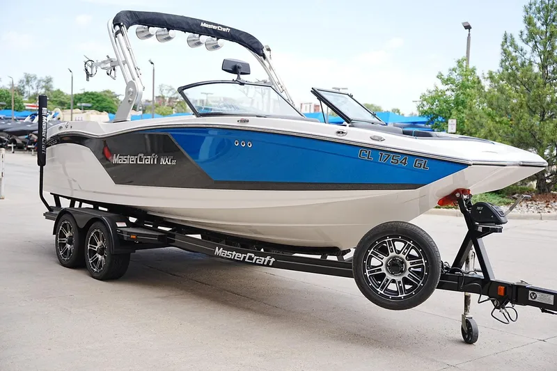 Slide: The Image of 2019 MasterCraft NXT22 boat on trailer, blue and white design, parked outdoors. - 5