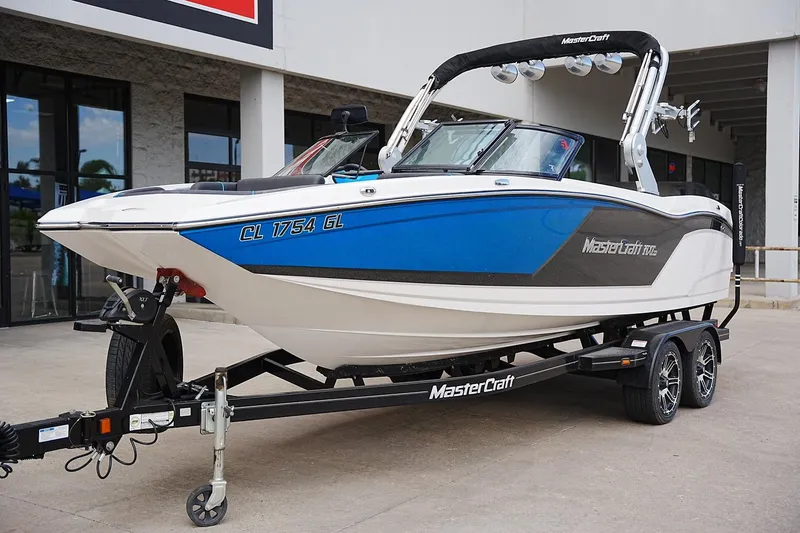 Slide: The Image of 2019 MasterCraft NXT22 boat on trailer, blue and white design, parked outdoors. - 6
