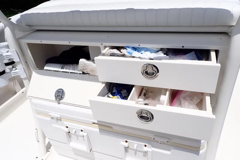 Slide: The Image of Storage compartments on a 2015 Century 2301 Center Console boat, featuring open drawers and supplies. - 33