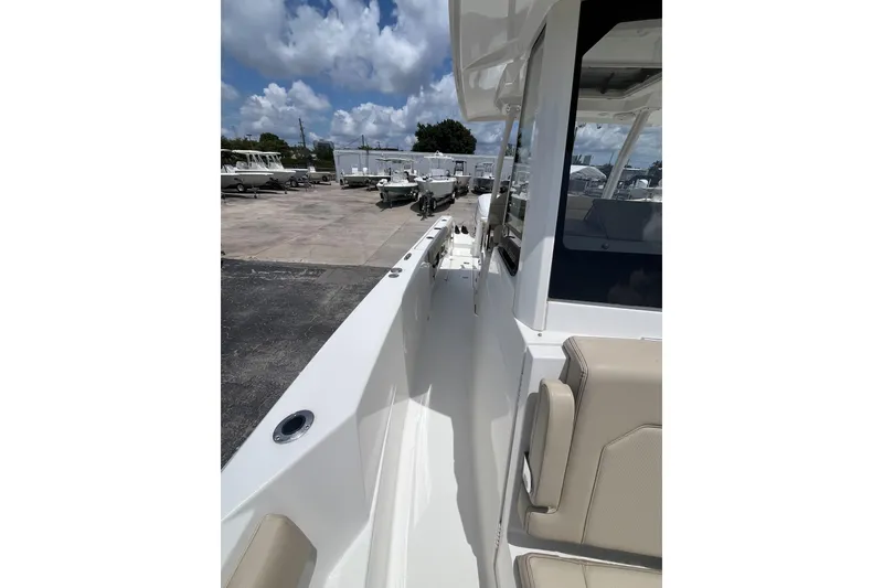 Slide: The Image of 2019 Pursuit S 288 Sport boat deck with beige seating under a cloudy sky. - 9