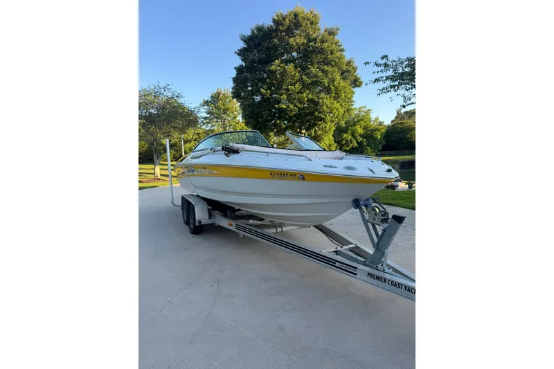 The Image of 2005 Crownline 210 Razor boat on trailer, parked outdoors with trees in background. - 0