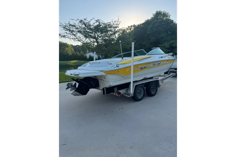 Slide: The Image of 2005 Crownline 210 Razor boat on trailer, parked outdoors, with yellow and white design. - 1