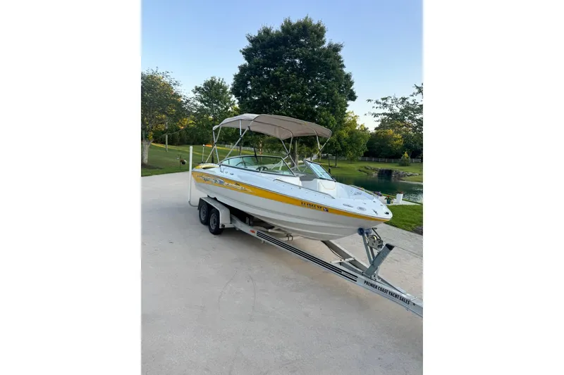 Slide: The Image of 2005 Crownline 210 Razor boat on trailer, parked outdoors with trees in background. - 15