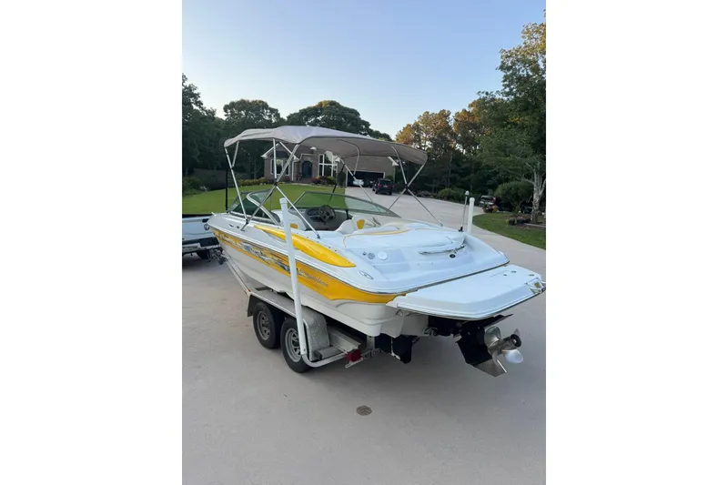 Slide: The Image of 2005 Crownline 210 Razor boat with yellow accents on a trailer in a driveway. - 16
