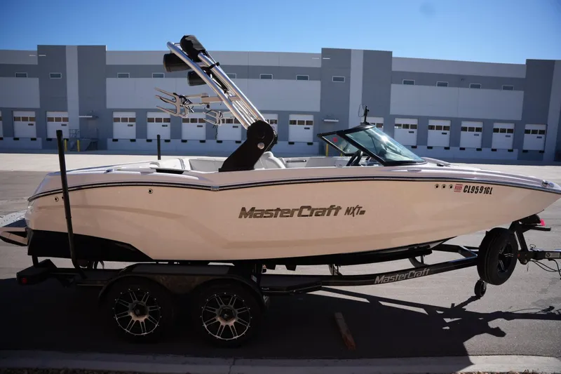 Slide: The Image of 2020 MasterCraft NXT20 boat on trailer, parked in industrial area. - 5