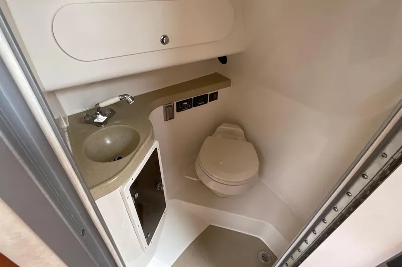 Slide: The Image of Compact bathroom in 2005 Seaswirl Striper 2901 Walkaround O/B boat, featuring sink and toilet. - 14
