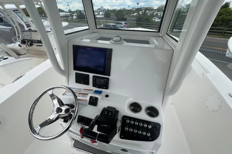 Slide: The Image of 2022 NauticStar 28 XS boat helm with steering wheel, controls, and navigation display. - 10