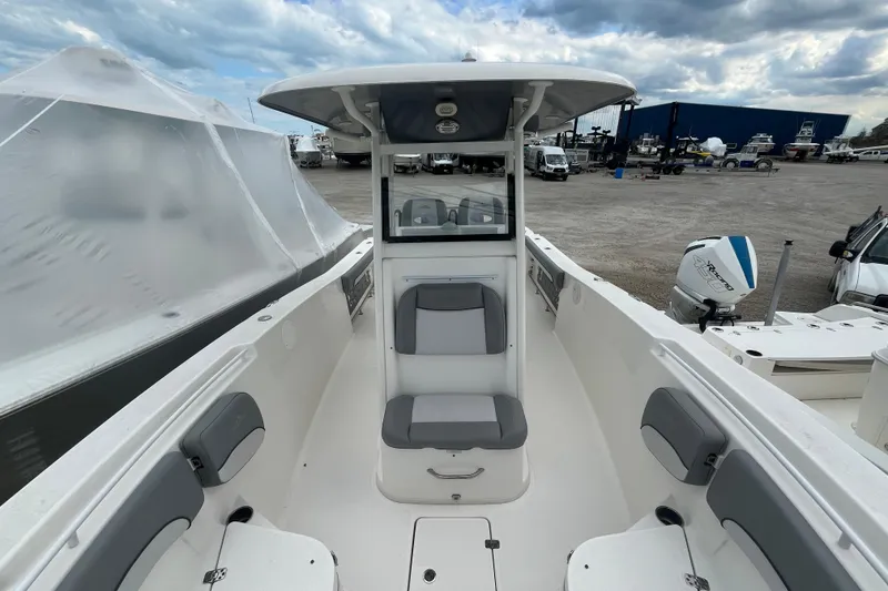 Slide: The Image of 2022 NauticStar 28 XS boat interior with seating and console, docked under cloudy sky. - 6