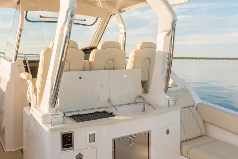Slide: The Image of Manufacturer Provided Image: 2026 Regal 33 SAV boat interior with seating, sink, and grill on a calm water backdrop. - 9