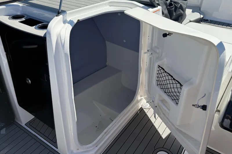 Slide: The Image of 2023 Yamaha Boats AR250 storage compartment with open door and netted pocket. - 24