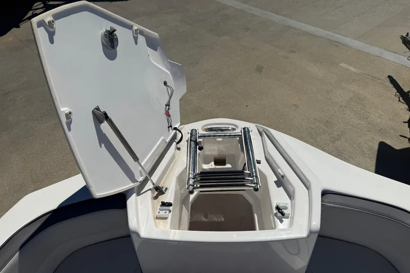 Slide: The Image of 2023 Yamaha Boats AR250 bow storage compartment with ladder, open on a sunny day. - 8