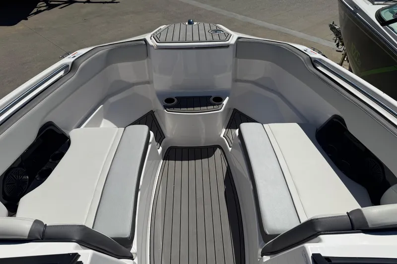 Slide: The Image of 2023 Yamaha Boats AR250 bow seating area with gray cushions and cup holders. - 9