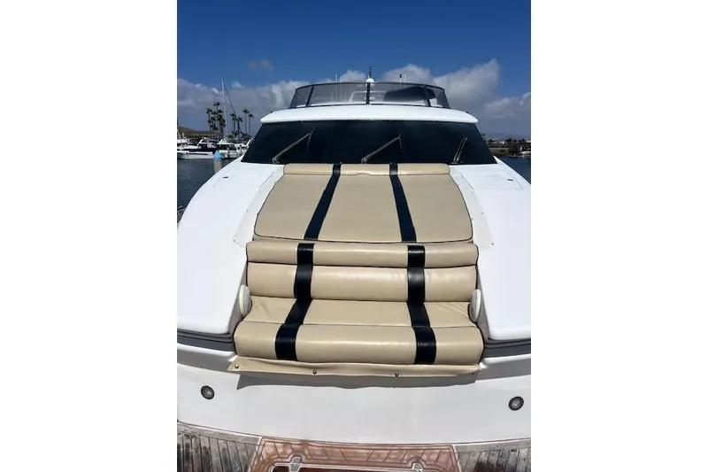 Slide: The Image of 1999 Horizon 70 Motor Yacht with beige and black deck cushions, docked under a clear sky. - 76
