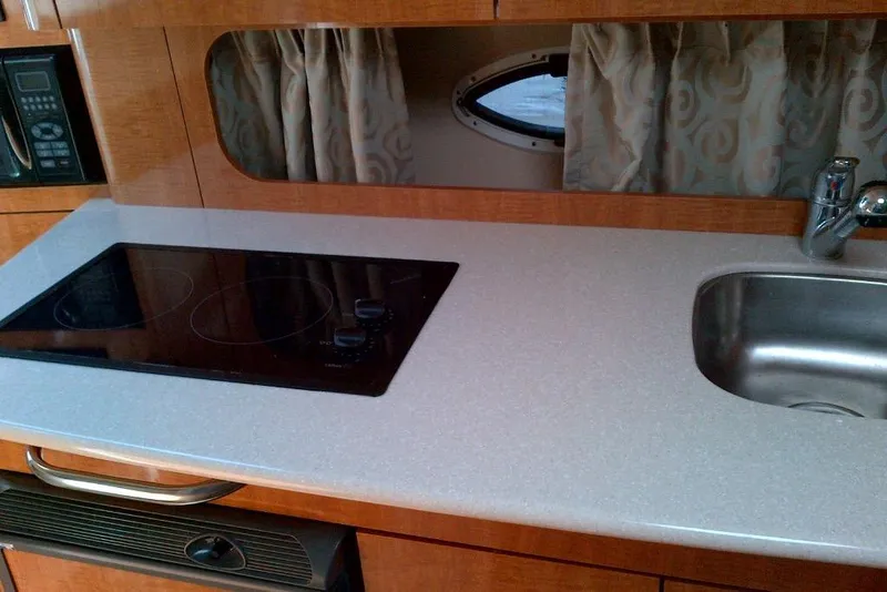 Slide: The Image of 2003 Maxum 2900 SCR boat kitchen with stove, sink, and microwave. - 11