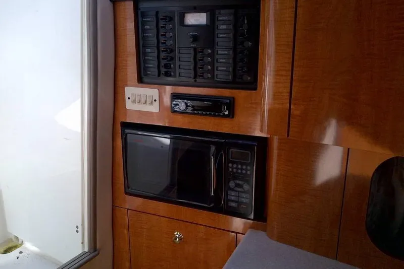 Slide: The Image of 2003 Maxum 2900 SCR interior with control panel, microwave, and wooden cabinetry. - 7